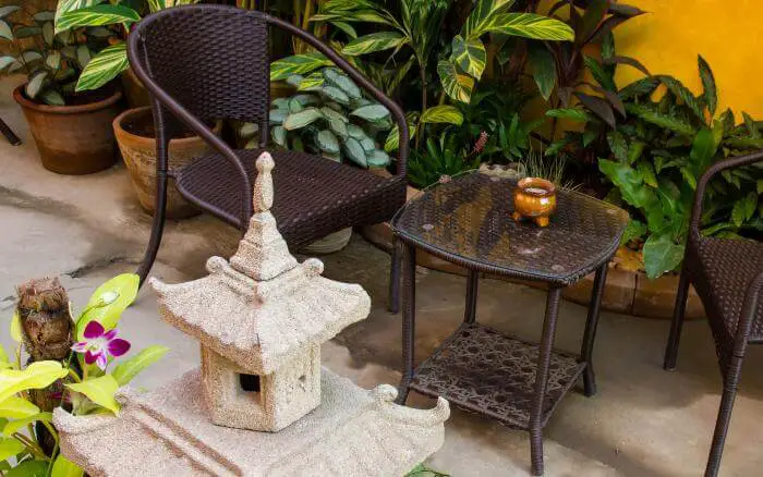 Jardim sombreado, com decoração em estilo asiático, com flores de Vinca Major e folhagens coloridas.