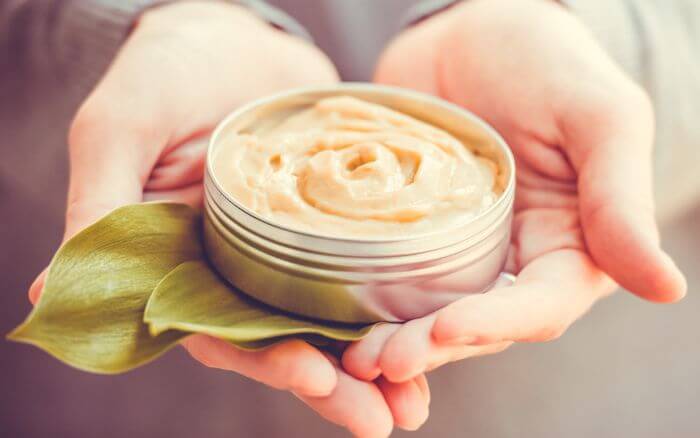 Pessoa segurando um cosmético artesanal de textura cremosa.