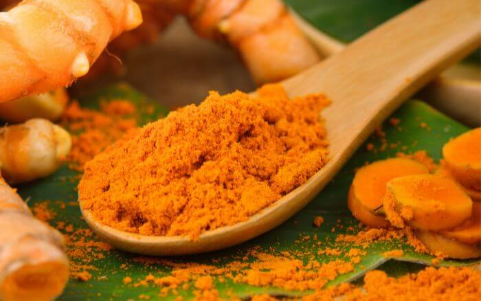 Cúrcuma especiaria em pó e em forma de raiz.